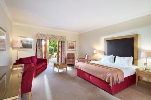 a hotel room with a large bed and a red couch at Inverness Lochardil House, by Highland Coast Hotels in Inverness