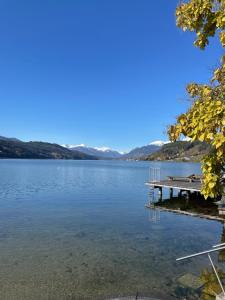 a dock on a lake with mountains in the background at Ferienwohnungen Seerose in Dellach direkt am Millstätter See in Millstatt