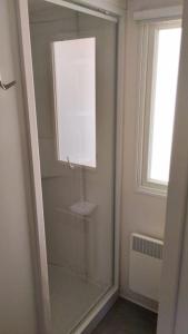 La salle de bains est pourvue d'une douche en verre et d'une fenêtre. dans l'établissement Mobil-home FO 18 à Vias, à Vias