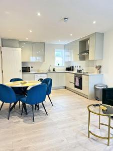 a kitchen with a table and blue chairs in a kitchen at Heathrow Charge and Go-FREE PARKING-Electric vehicle charging- Near Heathrow airport 5 min drive-Near Restaurants-Near Tesco Extra- Pet Friendly in Stanwell
