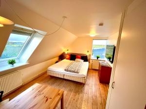 a small bedroom with a bed and two windows at Høloftet bb in Esbjerg