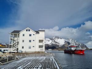 a boat is docked next to a white building at Apartment with fantastic seaview in Henningsvær. in Henningsvær