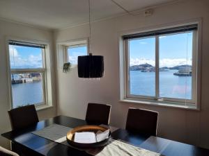 a dining room with a table and two windows at Apartment with fantastic seaview in Henningsvær. in Henningsvær