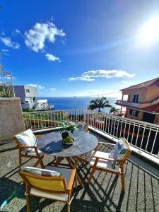 un patio avec une table et des chaises et l'océan dans l'établissement Sunshine Palace Madeira, à Ponta do Sol