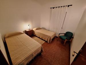 a bedroom with two beds and a green chair at Quinta São José in Coruche