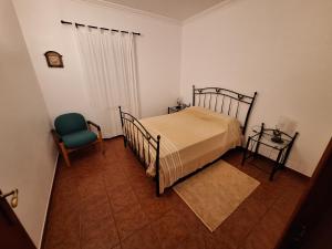 a bedroom with a bed and a green chair at Quinta São José in Coruche