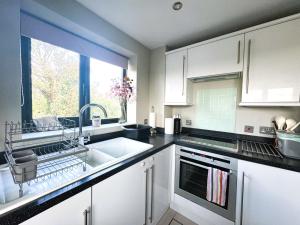 a kitchen with white cabinets and a sink and a window at Urban Oasis in Billericay