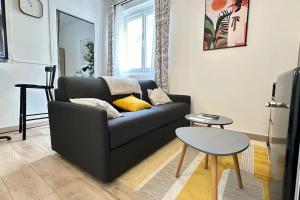 ein Wohnzimmer mit einem schwarzen Sofa und einem Tisch in der Unterkunft Le Cocon Douillet - 5" de la gare - WiFi - Accès direct Paris & Disneyland in La Ferté-sous-Jouarre