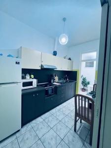 a kitchen with black cabinets and a white refrigerator at HARBOR house in Kavála