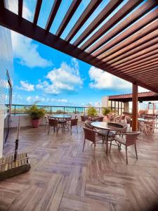 patio ze stołami i krzesłami oraz widokiem na ocean w obiekcie Apartamento na praia de Ponta de Campina w mieście Cabedelo