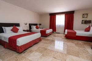 a hotel room with two beds and red curtains at Hotel Ocean View in Campeche