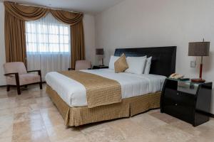 a hotel room with a large bed and a chair at Hotel Ocean View in Campeche