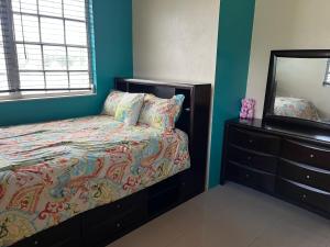 1 dormitorio con cama, tocador y espejo en Krizia Place, en Nassau