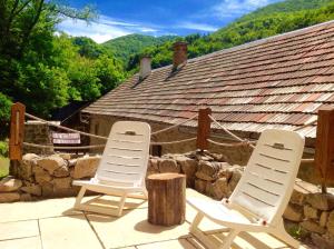 two chairs sitting on a patio with a stone wall at Kamenná chalupa in Hodruša