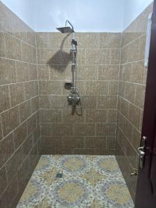 a bathroom with a shower with a tile floor at Grande Villa neuve 3 chambres avec piscine et wifi à Malikounda près Saly in Malikounda