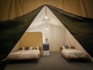 1 dormitorio con 2 camas en una tienda de campaña en Glampin By Tharu Garden en Sauraha
