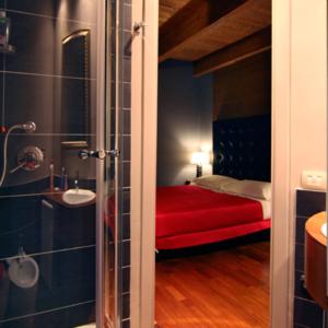 a bathroom with a shower and a red bed in a room at B&B La Dimora Della Zarina in Mormanno