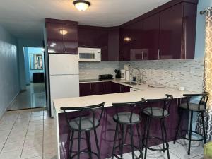 uma cozinha com armários roxos e um balcão com bancos de bar em 3BR, 1BA Spacious Property in Cataño, Near Bacardí em Catano