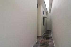 an alley way with white walls and a tile floor at SPOT ON The Greenwoods Retreat in Jhājra