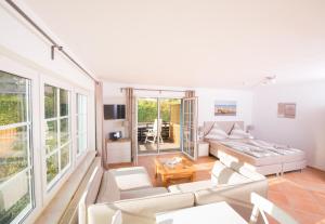 a living room with white furniture and large windows at Hotel Seebrise Grömitz in Grömitz