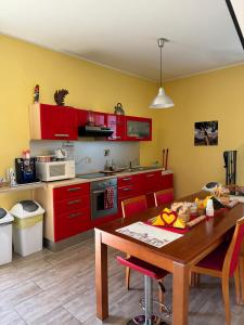 een keuken met rode kasten en een houten tafel bij LA TERRAZZA SU ROMA in Zagarolo