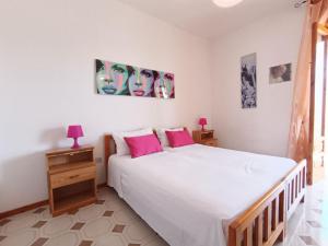 1 dormitorio con 1 cama blanca grande con almohadas rosas en Casa Relax a 200m dal mare, en Lido Marini