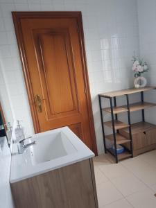 a bathroom with a sink and a wooden door at Casa La Porriñesa in Porriño