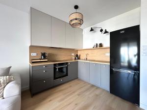 a kitchen with white cabinets and a black refrigerator at Apartament Lina Koralowa in Lublin