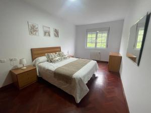 a bedroom with a large bed and two windows at Apartamento Castiñeira in Fisterra