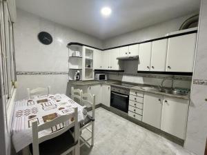 a kitchen with white cabinets and a table in it at Apartamento Castiñeira in Fisterra