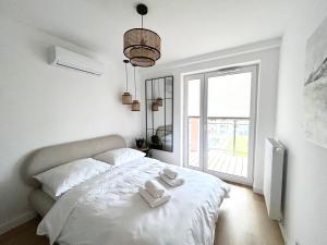 a white bedroom with a bed with towels on it at Apartament Lina Koralowa in Lublin