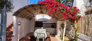 eine Terrasse mit einem Tisch und roten Blumen in einem Bogen in der Unterkunft Casa Vacanze Bouganville in Calasetta