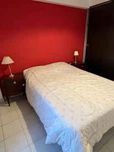 - une chambre dotée d'un lit avec un mur rouge dans l'établissement Departamento Jose, à San Miguel de Tucumán