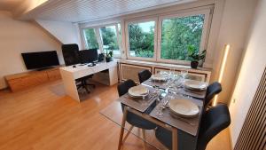 uma sala de jantar com uma mesa com cadeiras e uma secretária em Modern 2.5 Bedroom Duplex Apartment near Messe, Airport, Arena em Dusseldorf