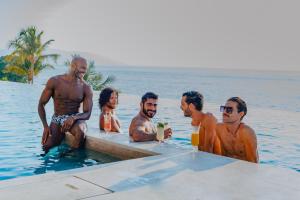 un groupe d'hommes assis dans l'eau dans l'établissement Almar Resort Luxury LGBT Beach Front Experience, à Puerto Vallarta