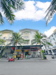 a building with palm trees in front of a street at Sunny Motel Tuần Châu in Ha Long