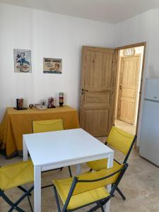 uma cozinha com uma mesa branca e duas cadeiras amarelas em Chambres indépendantes en plein centre historique em Beaucaire