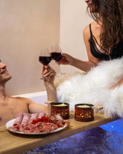 a man and woman sitting in a bath tub drinking wine at Minamina, chambre avec jacuzzi privatif in Roquefort-la-Bédoule