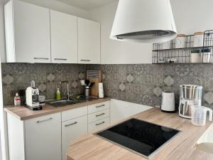 a kitchen with white cabinets and a wooden counter top at Neue Bodenseeferienwohnung mit Terrasse und Garten in Uhldingen-Mühlhofen