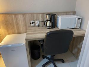 a desk with a microwave and a chair on it at Aquarius Flat Studio 509 in Santa Cruz do Sul