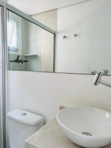 a white bathroom with a sink and a toilet at Apartamento a 100 m da praia in Juquei