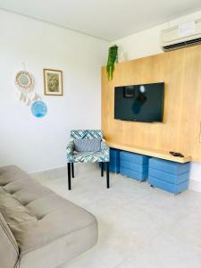 a living room with a couch and a tv on a wall at Apartamento a 100 m da praia in Juquei