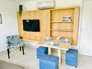 a dining room with a table and chairs and a tv at Apartamento a 100 m da praia in Juquei