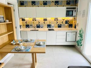 a kitchen with white cabinets and a table with dishes at Apartamento a 100 m da praia in Juquei