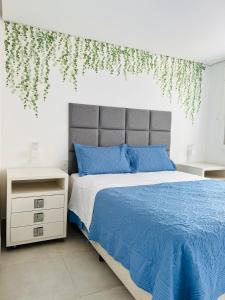a bedroom with a bed with blue pillows and ivy on the wall at Apartamento a 100 m da praia in Juquei