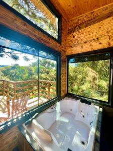 a bath tub in a room with two windows at Flor da serra in Urubici +171 photos