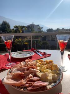 um prato de carne e queijo numa mesa com copos de vinho em Ferienwohnung "Casa Annabella" em Ascona
