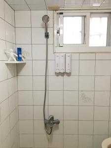 um chuveiro numa casa de banho em azulejos brancos em Liuqiu Cozy Room em Xiaoliuqiu