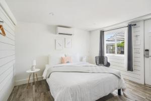 a white bedroom with a bed and a window at Breakers Montauk in Montauk