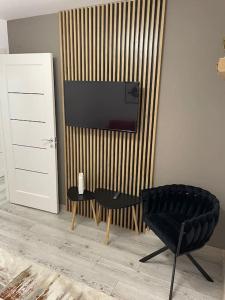 uma sala de estar com uma cadeira preta e uma televisão em Apartament D&T em Vatra Dornei